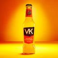 A bottle of VK Orange & Passion Fruit sparkling alcopop with a bright orange label, displayed against a orange background.