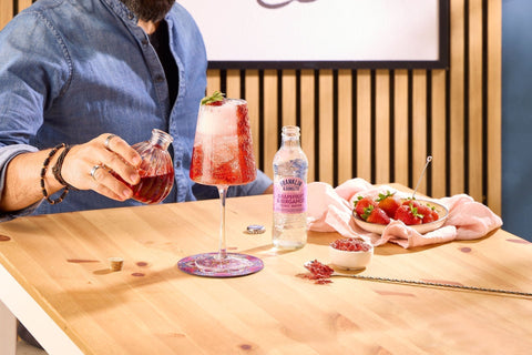 Someone making a strawberry cocktail using Franklin & Sons Grapefruit & Bergamot tonic.