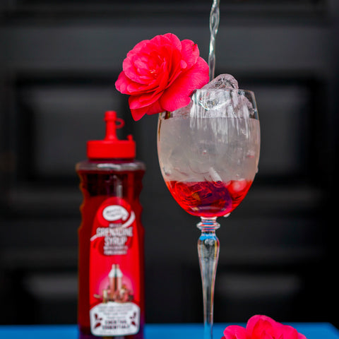 Someone making a cocktail using Master of mixes cocktail essentials grenadine syrup, perfect for making cocktails and mocktails. 