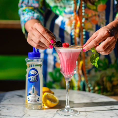 Someone making a cocktail using Master of mixes cocktail essentials simple syrup, perfect for making cocktails and mocktails. 