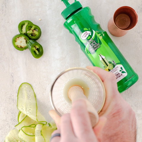 Someone making a cocktail using Master of mixes cocktail essentials lime juice, perfect for making cocktails and mocktails. 
