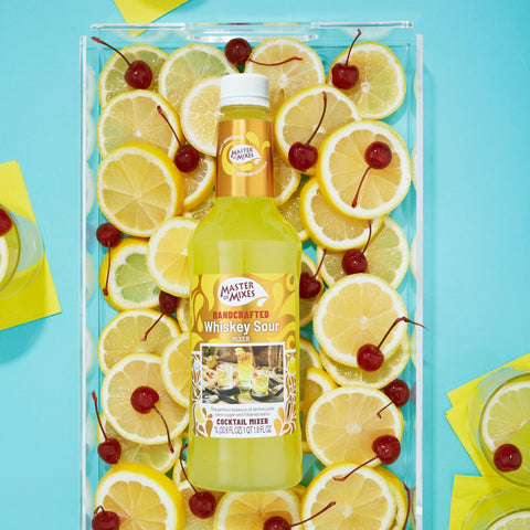 Bottle of Master of Mixes whiskey sour surrounded by lemon slices and cherries on a blue background.