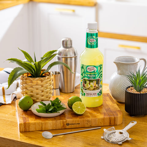 Bottle of Master of Mixes Mojito mix on a kitchen counter with ingredients and utensils.