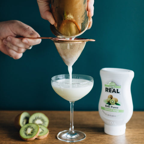 Someone making a cocktail using Real kiwi puree syrup, a vegan and gluten-free syrup which is a perfect cocktail or mocktail ingredient. 