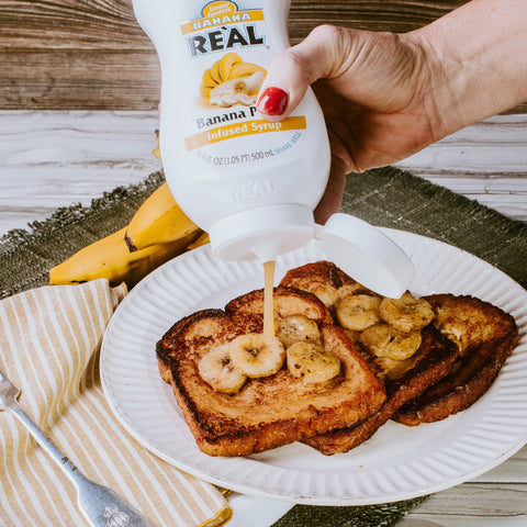 A person squeezing Real Banana Puree Syrup over French toast with bananas, Real syrups are great for cooking & baking or making cocktails.
