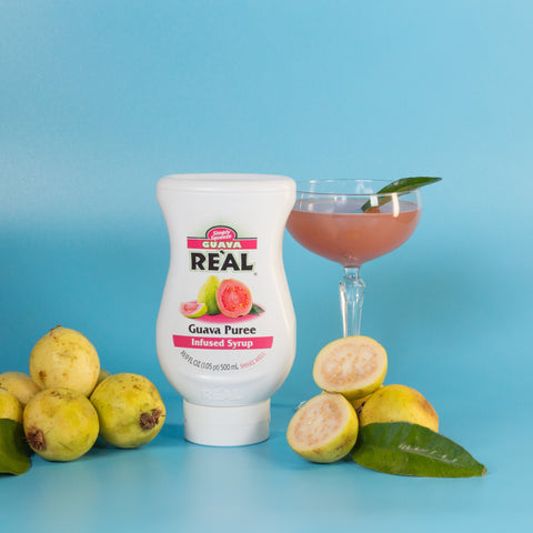 A guava cocktail made using Real guava syrup, with the syrup bottle next to the cocktail, Real syrups are gluten-free and vegan and are the perfect cocktail or mocktail ingredients. 