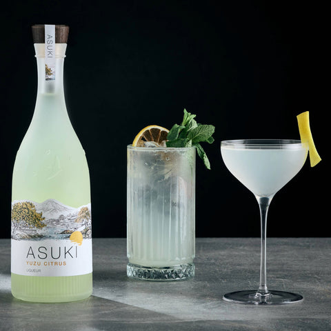 Two yuzu cocktails made with Asuki Yuzu Citrus Liqueur, with the bottle of Asuki placed next to the two cocktails. 