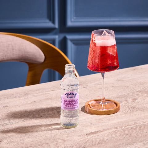 A bottle of Franklin & Sons grapefruit & bergamot tonic water, next to a glass where the tonic has been used as a premium mixer. 