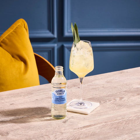 A glass bottle of Franklin & Sons 1886 original lemonade, being used as a premium mixer in the drink next to it. 