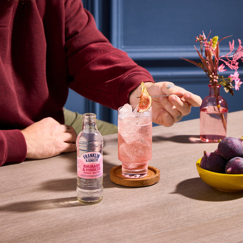 Franklin & Sons rhubarb & hibiscus tonic water being used as a premium mixer in the glass next to the bottle. 