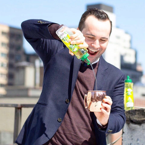 A man making a Mule cocktail using Master of Mixes Cocktail Essentials Sweetened Lime Juice syrup . 