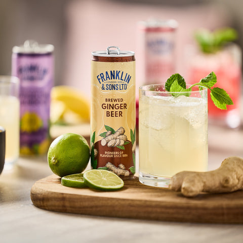 Franklin & Sons Ltd ginger beer can with a glass of ginger beer on a wooden board, surrounded by ingredients.