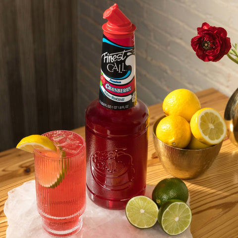 A cranberry cocktail made with Finest Call Premium Cranberry Juice Mix, with the Finest Call bottle behind the cocktail. 