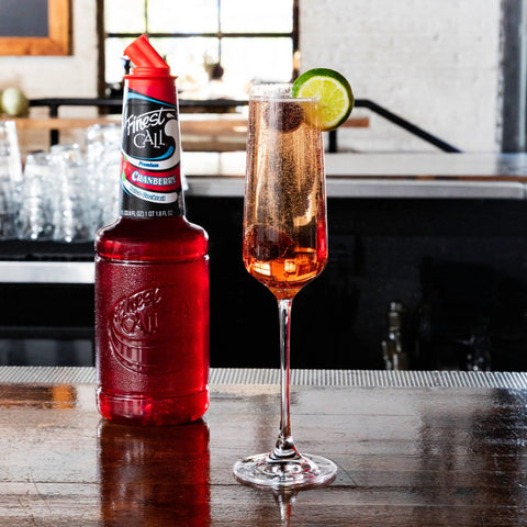 A cranberry sparkling wine made with Finest Call Premium Cranberry juice mix, with the Finest Call bottle behind the drink. 