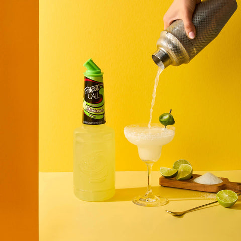 Person pouring a margarita into a glass with a bottle of Finest Call Margarita.