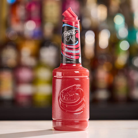 Red bottle of Finest Call Raspberry Puree on a bar counter with blurred bottles in the background