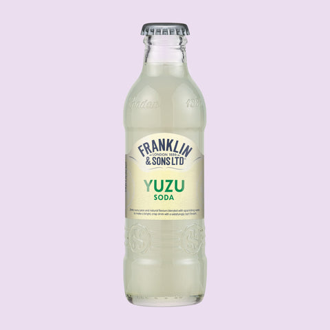 Glass bottle of Franklin & Sons Ltd Yuzu Soda on a light purple background