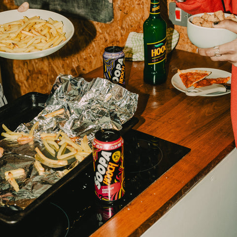 Food on a table at a party with Soopa Hooch cherry cola ready to drink can next to the food. 