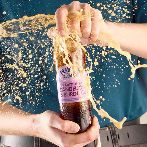Person opening a bottle of Franklin & Sons Dandelion & Burdock with a splash effect.