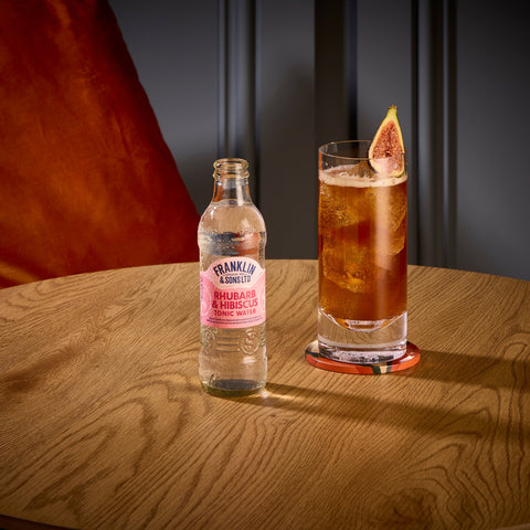 A bottle of Franklin & Sons rhubarb & hibiscus tonic water being used as a premium mixer in the glass next to the bottle. 
