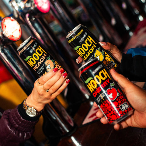 People holding three cans of Hooch premixed and ready to drink alcopops. 