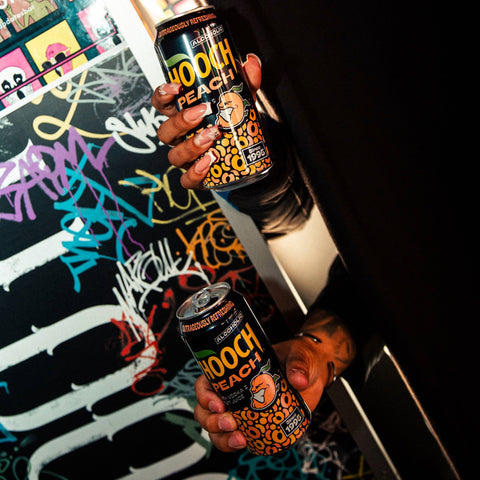 People holding two cans of Hooch Peach, a peach alcoholic lemonade premixed with vodka and fruit juice. 