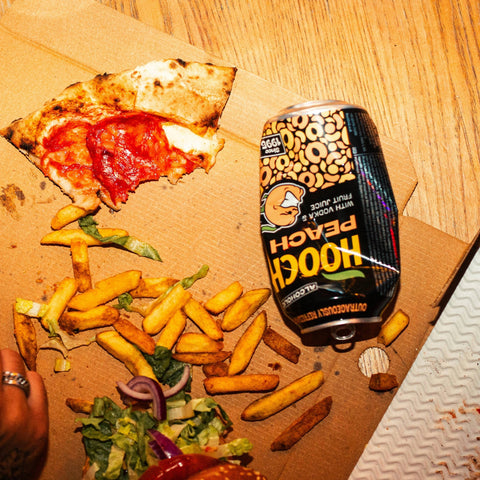 A can of Hooch Peach, premixed alcopop next to food. 