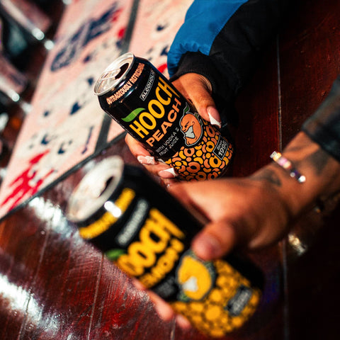 People holding two cans of Hooch premixed and ready to drink alcopops 