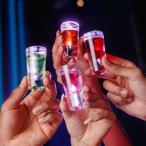 People holding shots of Corky's sour schnapps in different flavours and colours. 