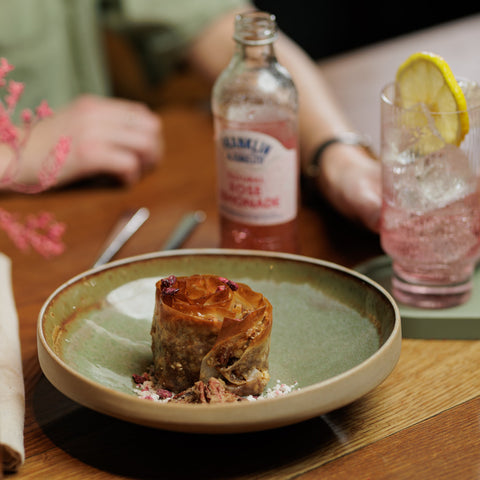 Someone drinking Franklin & Sons natural rose lemonade, a premium soft drink at a restaurant. 