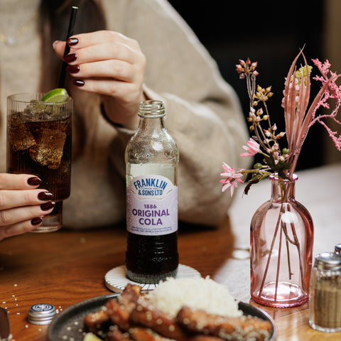 Someone at a restaurant drinking Franklin & Sons 1886 original cola, a premium soft drink. 