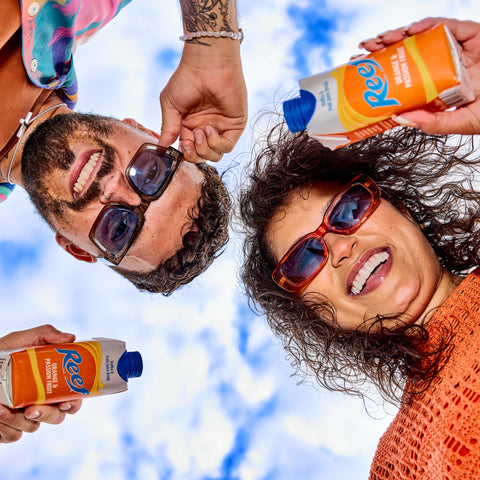 Two people holding ready to drink, pre mixed Reef orange and passion fruit. 