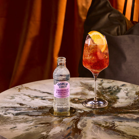 A bottle of Franklin & Sons grapefruit & bergamot tonic water, next to a glass where the tonic has been used as a premium mixer. 