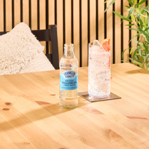 A bottle of Franklin & Sons original Mallorcan tonic water, with a glass of the tonic water next to the bottle.