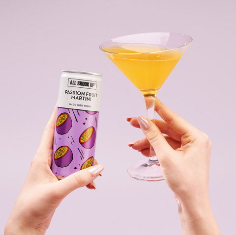 Someone holding a cocktail glass that has All Shook Up passion fruit martini premixed, ready to drink canned cocktail poured into it. 