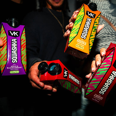 Four Squashka drinks held by a person against a dark background