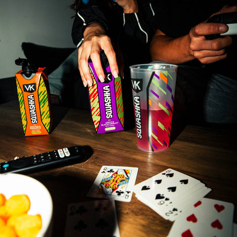 VK Squashka drinks and cards on a table with a person holding a phone.