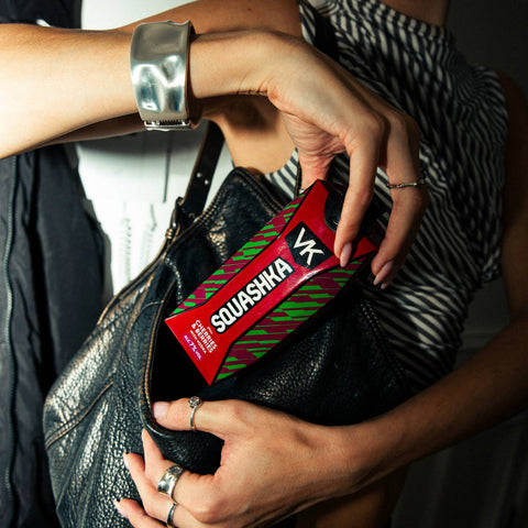 Person holding a black leather bag with a Squashka VK drink inside