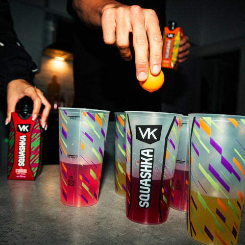 Squashka drinks being poured into colorful cups with a dark background