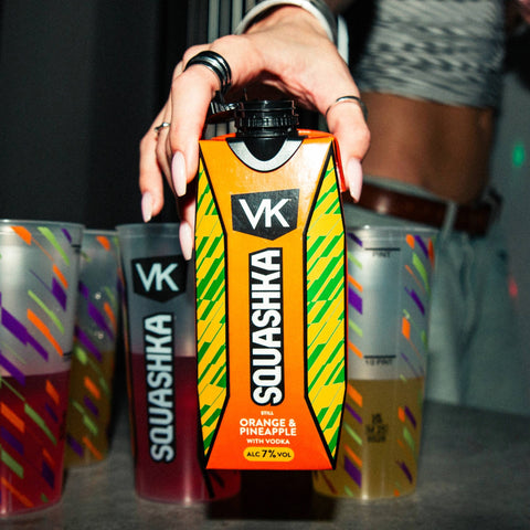 Person holding a colorful Squashka drink container with 'VK' branding.