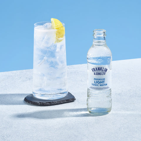 A bottle of Franklin & Sons premium light tonic next to a glass that has used the tonic as a mixer. 