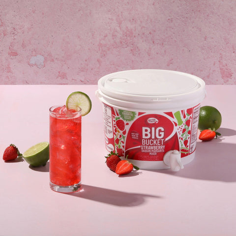 Master of Mixes strawberry big bucket next to a pink drink with strawberries and limes. 