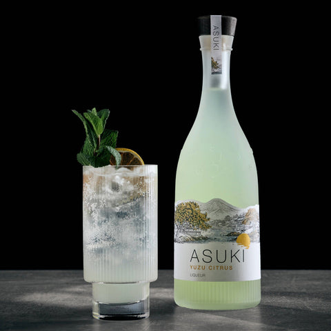 A yuzu spritz cocktail made with Asuki Yuzu Citrus Liqueur with the Asuki bottle placed next to the glass. 