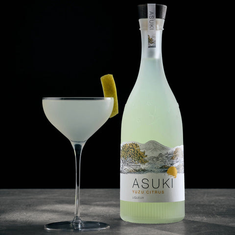 A yuzu cocktail made with Asuki Yuzu Citrus Liqueur, with the Asuki liqueur bottle placed next to the cocktail. 