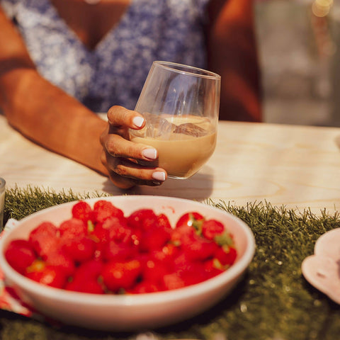 A person drinking Lustre Caffe Latte Vodka Cream Liqueur, a vegan cream liqueur with ice. 