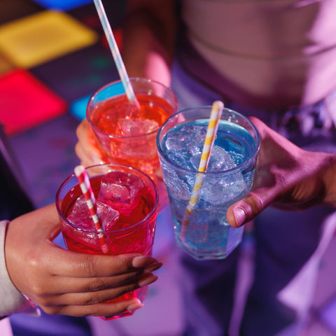 People holding multicoloured Corky's sour schnapps drinks at a party. 