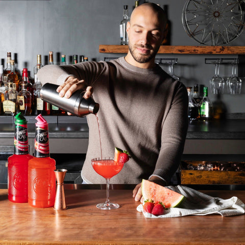 A person making a cocktail using Finest Call Raspberry mix. 