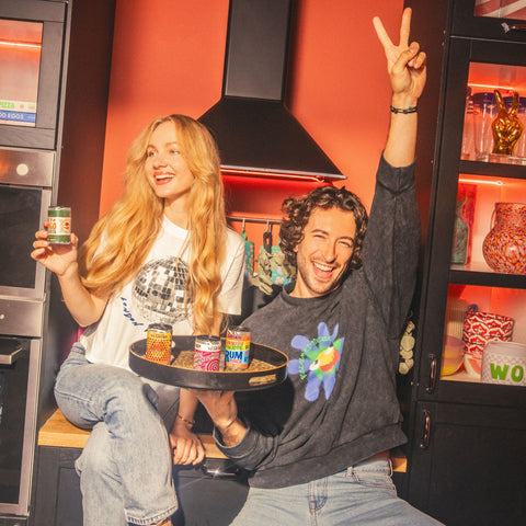Two people smiling holding GATHER cocktails in a kitchen. 
