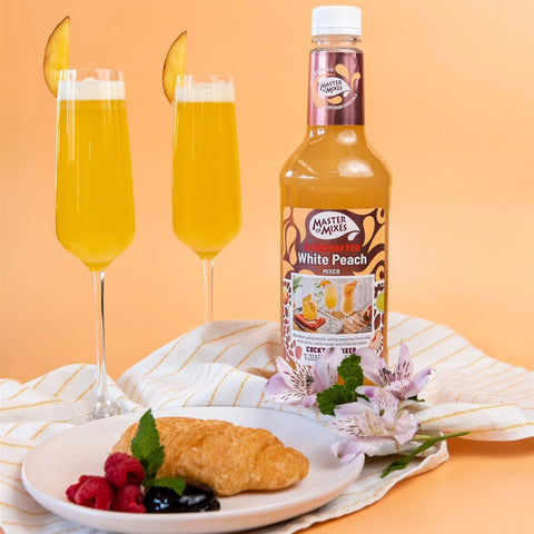 Two bellini cocktails made using Master of Mixes White Peach mixer, with the Master of Mixes bottle next to the drinks. 