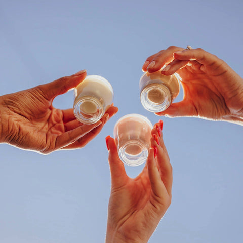 Three hands holding each flavour of Lustre vegan cream liqueurs. 